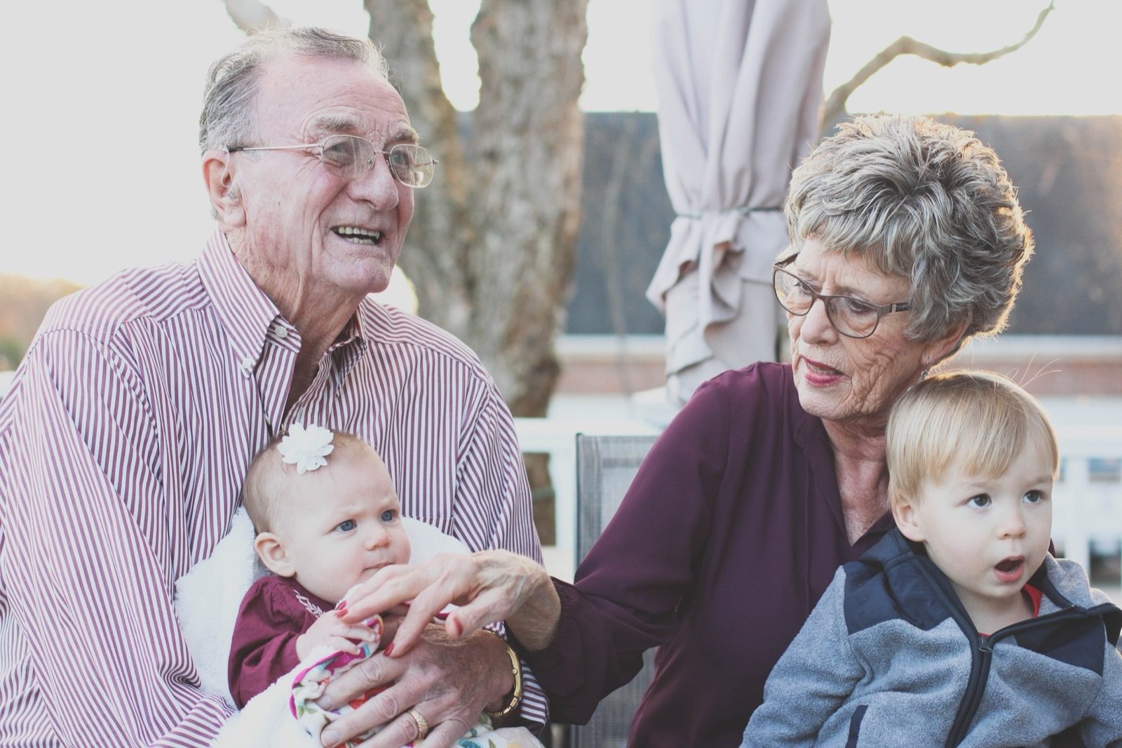 Grandparents holding two young grandchildren outdoors