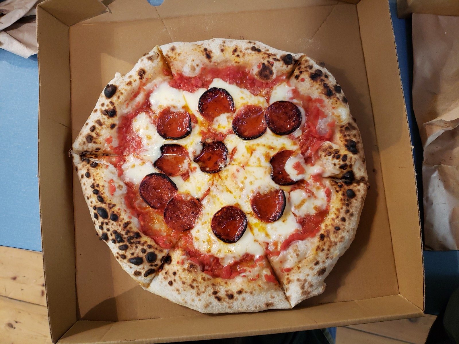 A pepperoni pizza with the pepperoni slices curled and browned at the edges