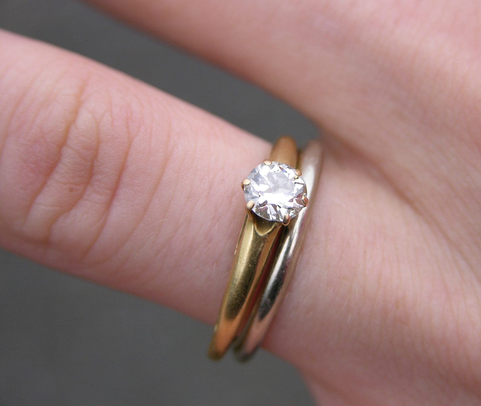 Close-up of a diamond engagement ring stacked with a wedding band on a hand